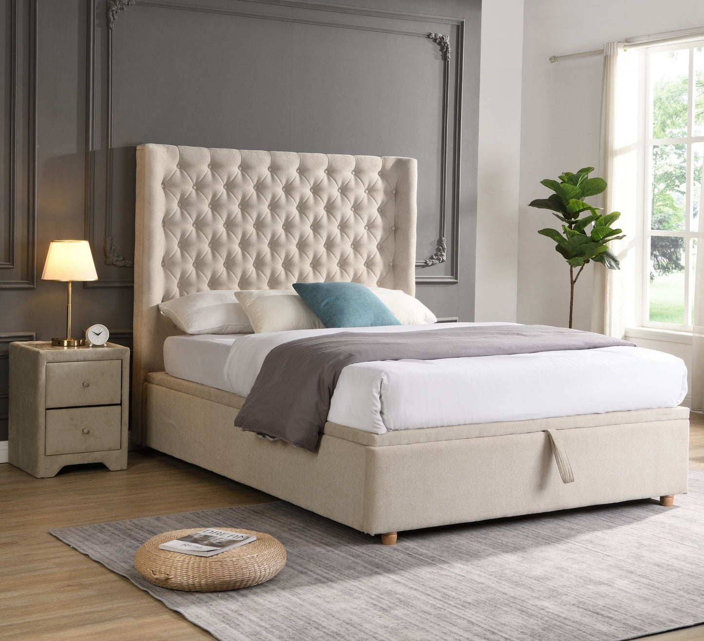 Beige upholstered bed in a modern bedroom with large windows and decorative elements.